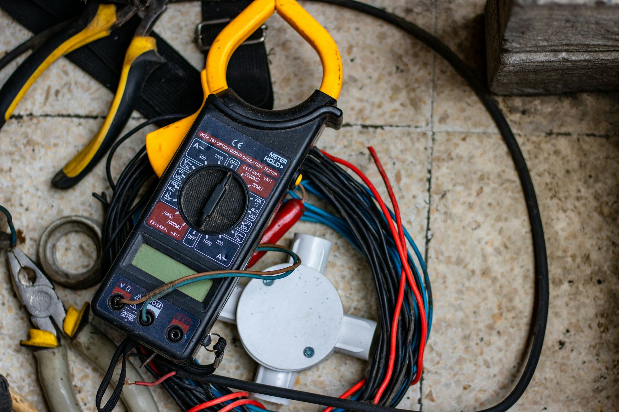 A clamp meter and test leads on a workbench