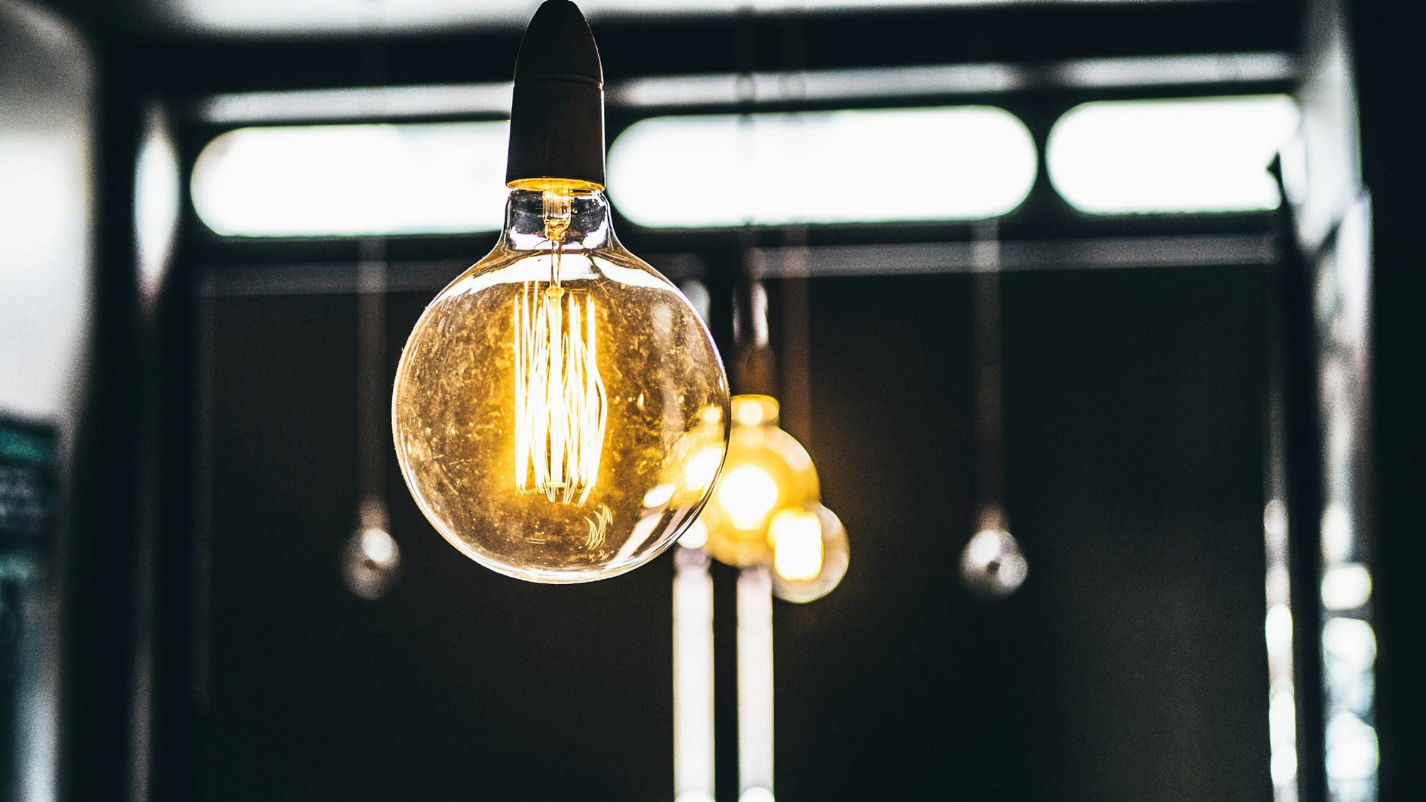 A clear filament light bulb glowing against a dark background