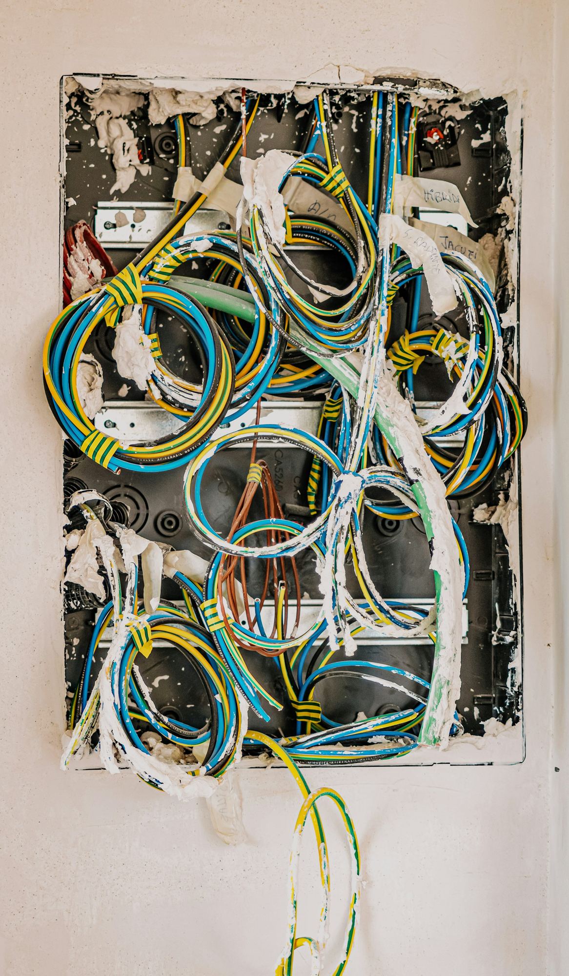 Yellow, blue and black coated wires coming out of a wall